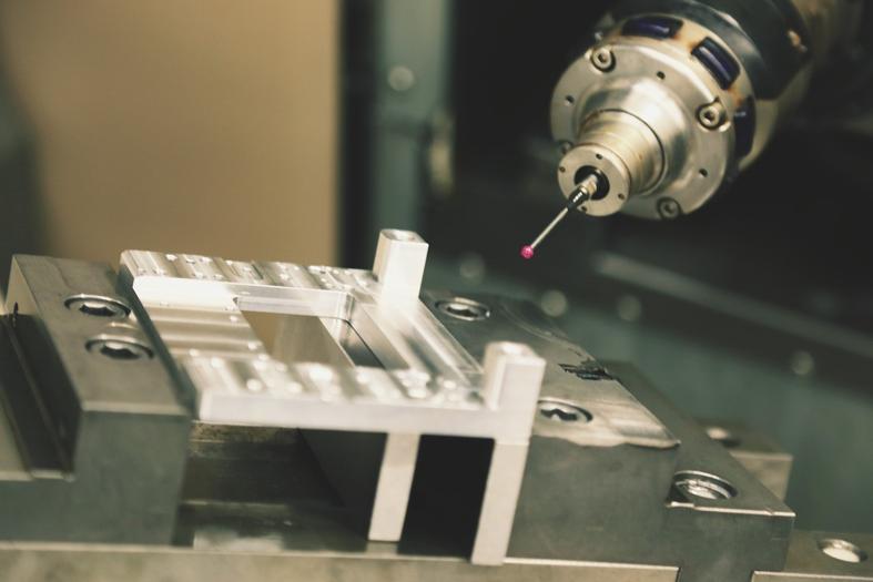 Precision CNC milling machine in action, showcasing a metal part being measured with a probe.